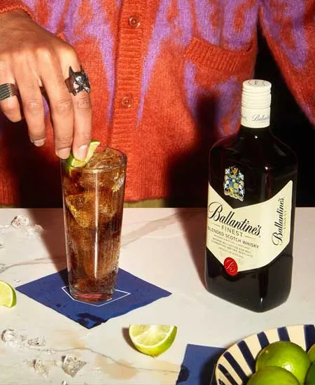 Foto de Ballantines Finest x 700ml en una mesa con un coctel y una persona