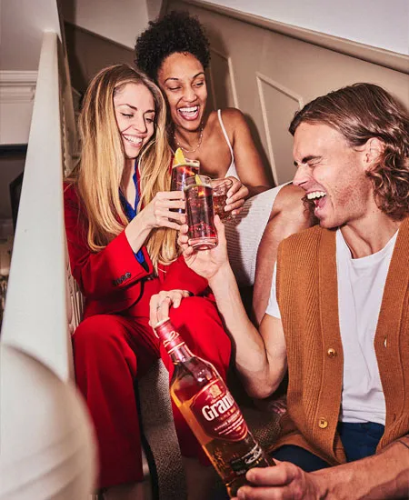 Foto de amigos tomando en una escalera y brindando con Grants Triple Wood x 1000ml