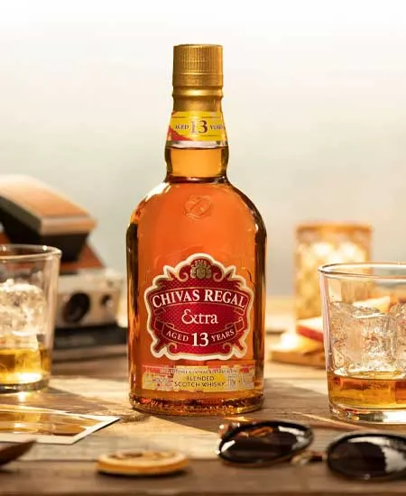 Foto de Chivas Extra 13 años x 700ml en mesa con cocteles y gafas