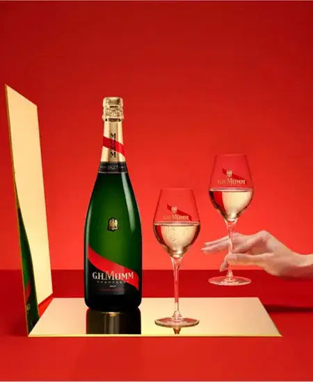 Mumm Cordon Rouge fotografia de botella en fondo rojo con copas y una mano
