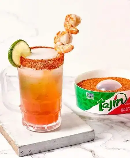 Tajín Clásico Escarchador x 120grs con coctel en copa limon y camarones sobre una tabla blanca