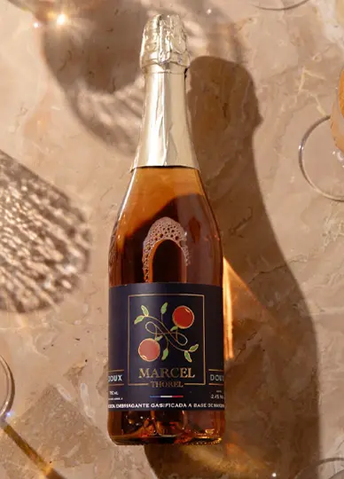 Sidra Marcel Thorel Doux Artesanal x 750ml en mesa con copas plano cenital