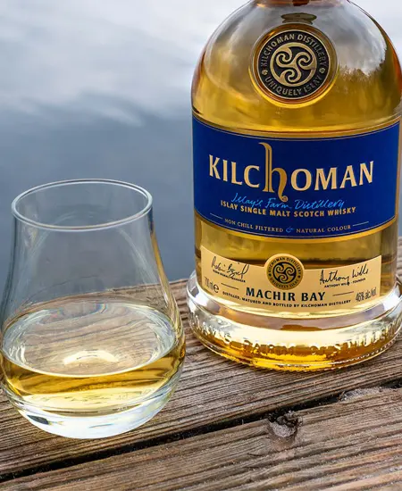 Foto de Kilchoman Machir Bay x 750ML en madera con copa y fondo de agua